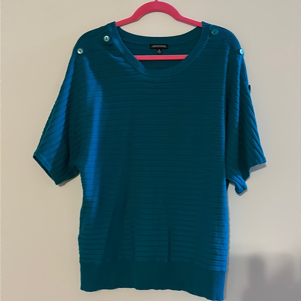 Green light sweater with buttons on sleeves.